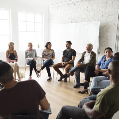 Group of people seated in a circle having a discussion in a casual setting