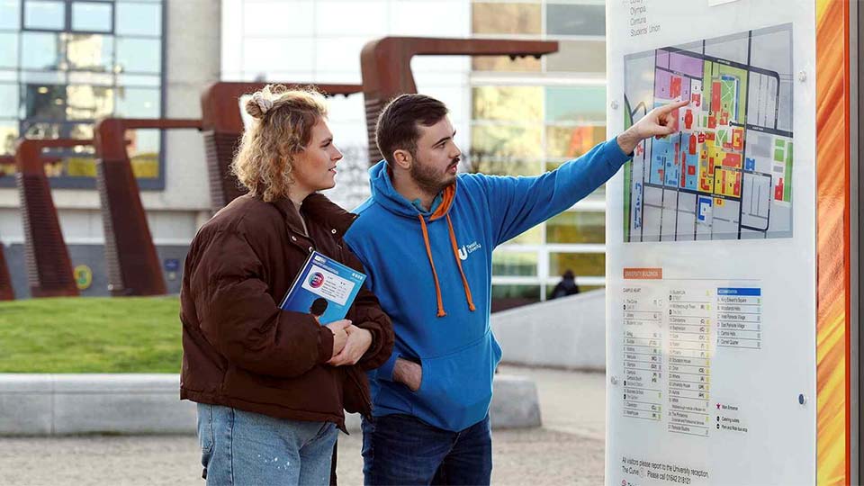 Student ambassador helping a visitor with a campus map at Teesside Universityâ€™s Campus Heart