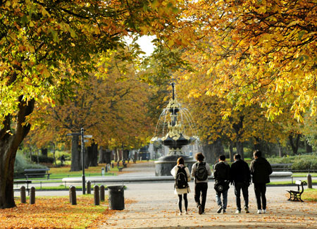 Autumn view of Albert Park with people walking toward the fountain