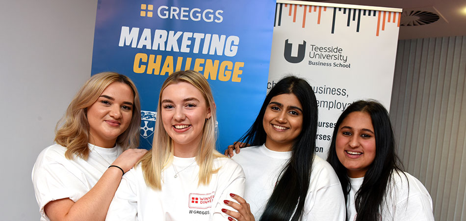 A team of Teesside University students that worked with Greggs to develop a new campaign concept in front of a Greggs stand