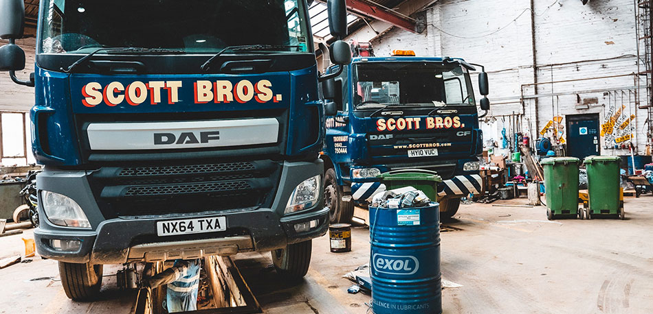 Two Scott Bros trucks in a garage undergoing maintenance