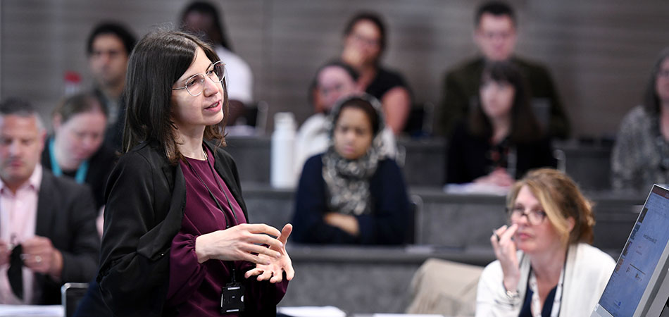 Person speaking at a conference with attendees listening