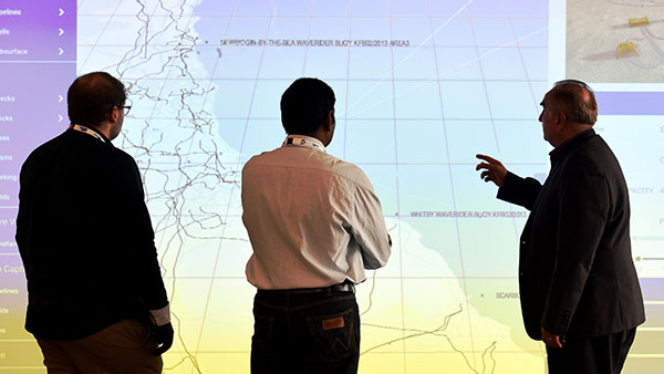 Teesside University staff in front of a wall screen displaying a map