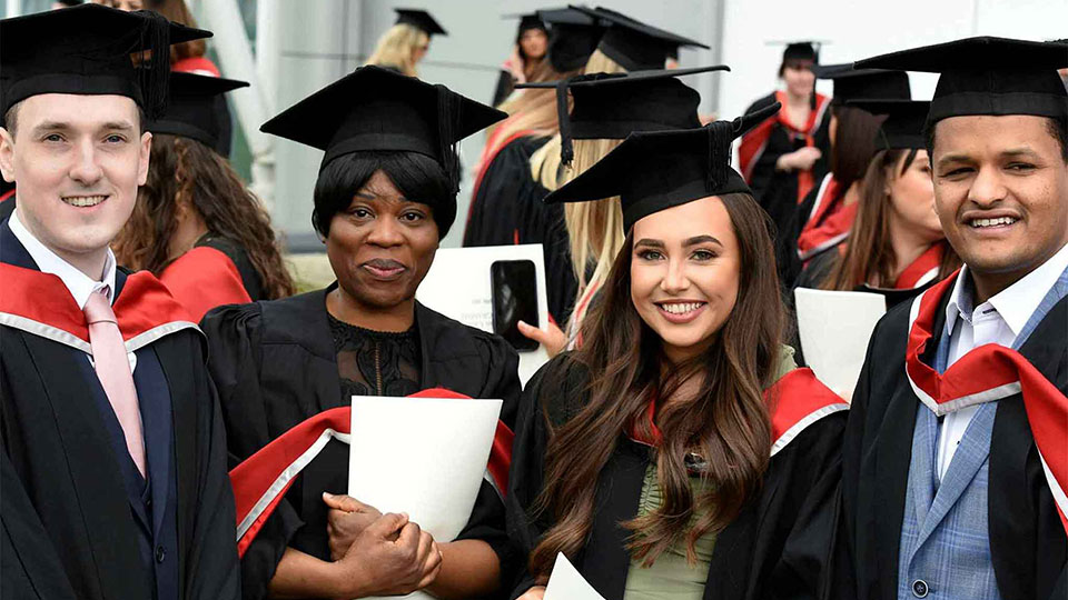 Graduates in academic gowns and caps celebrating at a graduation ceremony.