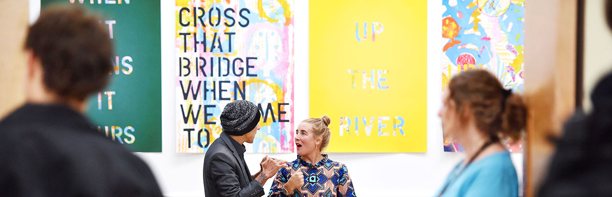 People attending an event or exhibition inside MIMA, with creative displays in the background.