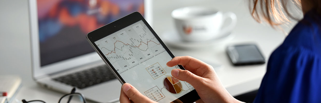 Woman holding a tablet showing financial graphs and data visualizations