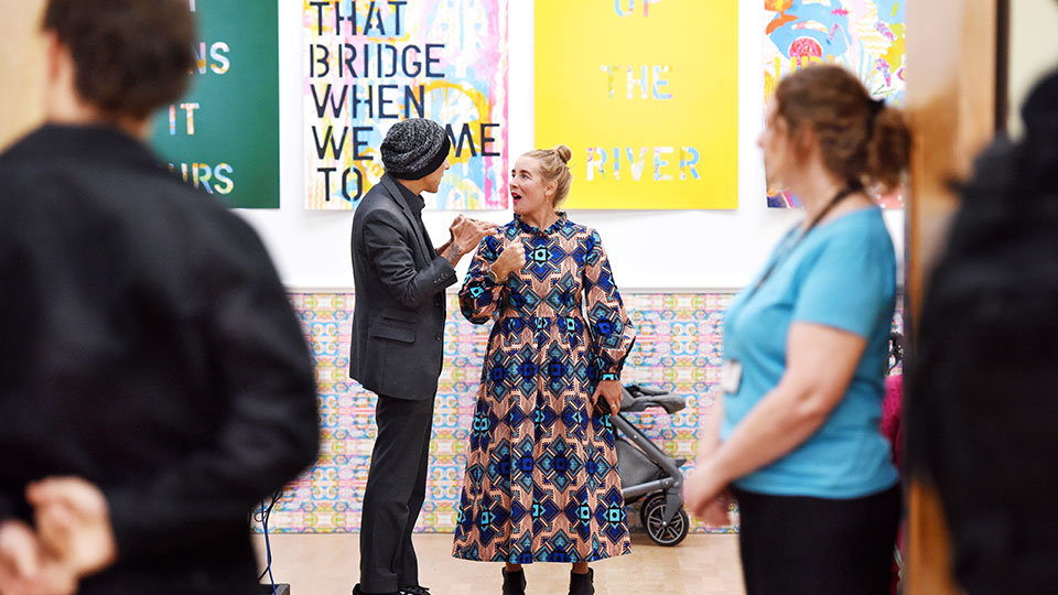 People attending an event or exhibition inside MIMA, with creative displays in the background.