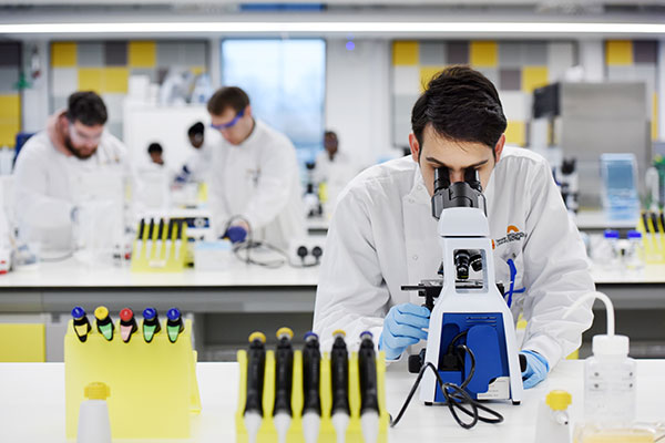Staff member using a microscope in a research lab at Teesside University